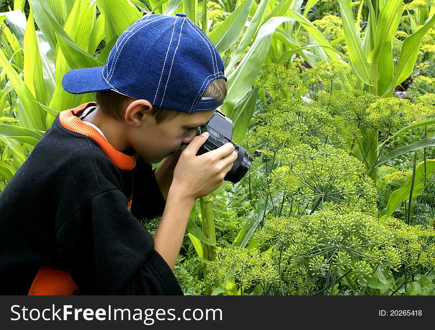 The boy with a camera is keen on shooting on the nature. The boy with a camera is keen on shooting on the nature.