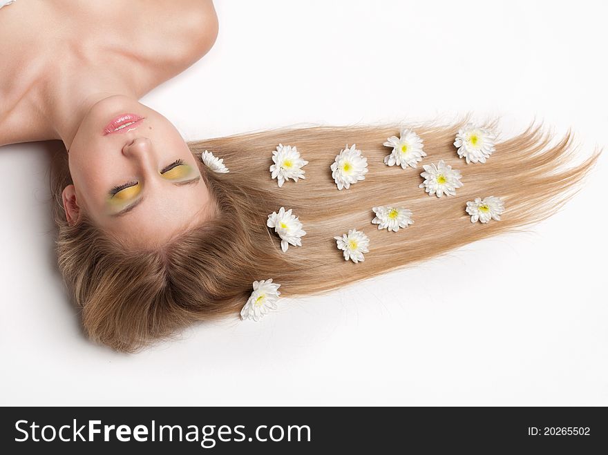 Attractive young woman lying covered with flowers