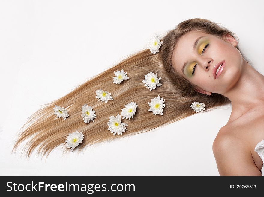 Attractive young woman lying on white background covered with flowers. Attractive young woman lying on white background covered with flowers