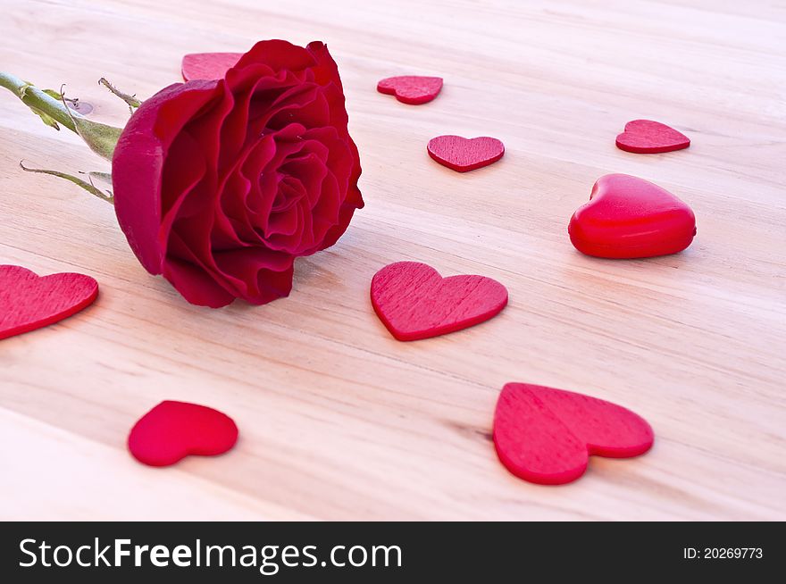 Red rose with hearts in wood background