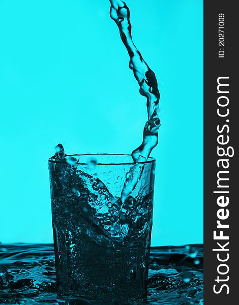 Liquid pouring into the glass over blue background