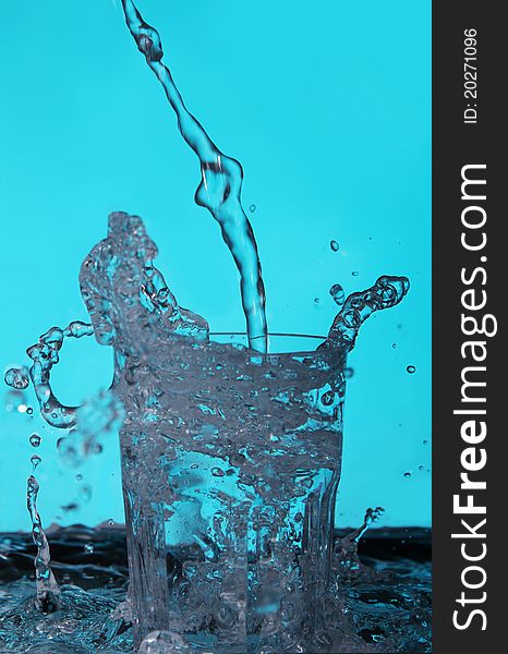 Liquid pouring into the glass over blue background