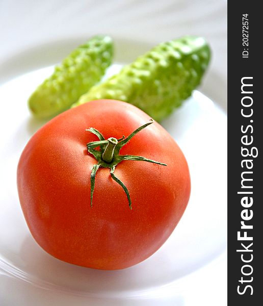 Tomato and cucumbers on white plate. Tomato and cucumbers on white plate