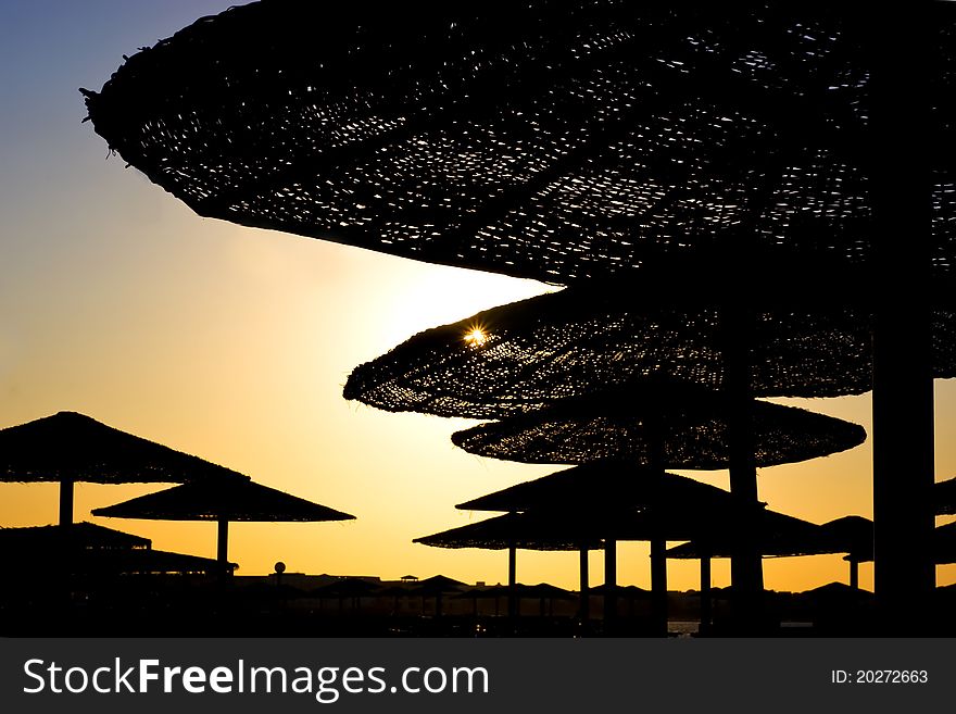 Silhouettes of beach's umbrellas at the sunset