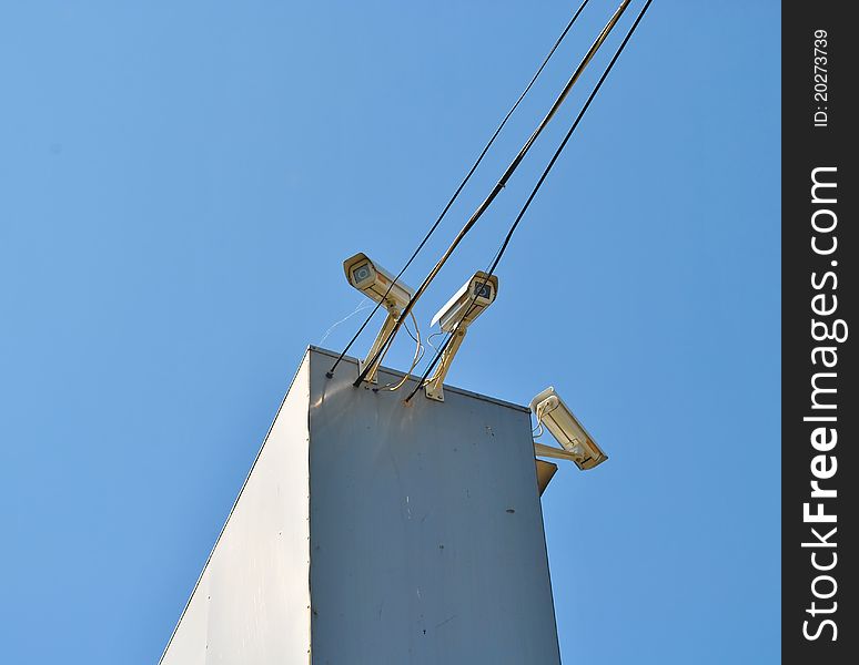 Three surveillance cameras against the sky