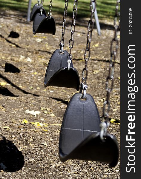 A set of swings in a much visited city park.