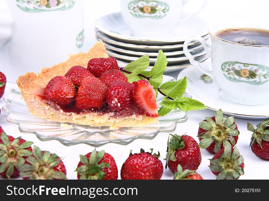 Strawberry tart, fruits, mint twig and a cup of tea