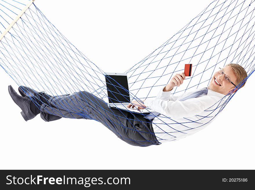 A young man with laptop and credit card is isolated in a hammock. A young man with laptop and credit card is isolated in a hammock