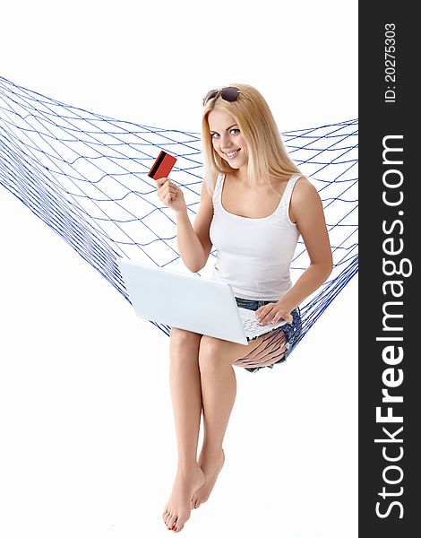 Attractive girl with laptop and credit card is isolated in a hammock