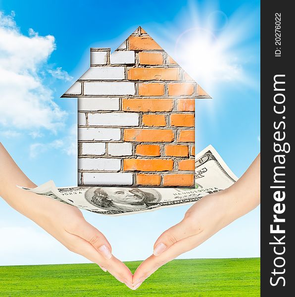 Hands holding model of a brick house on nature background