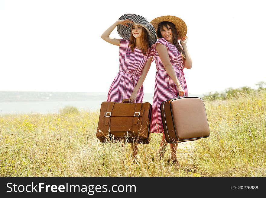 Two retro style girls with suitcases at countryside.
