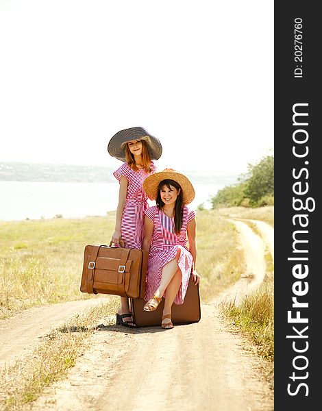 Two retro style girls with suitcases at countryside.