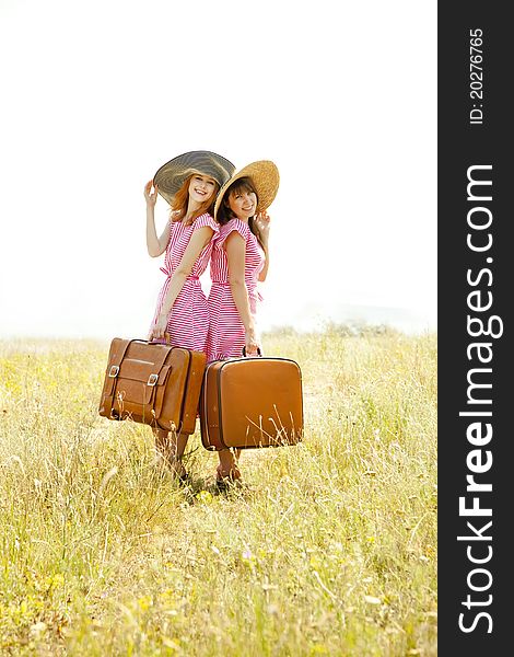 Two retro style girls with suitcases at countryside.