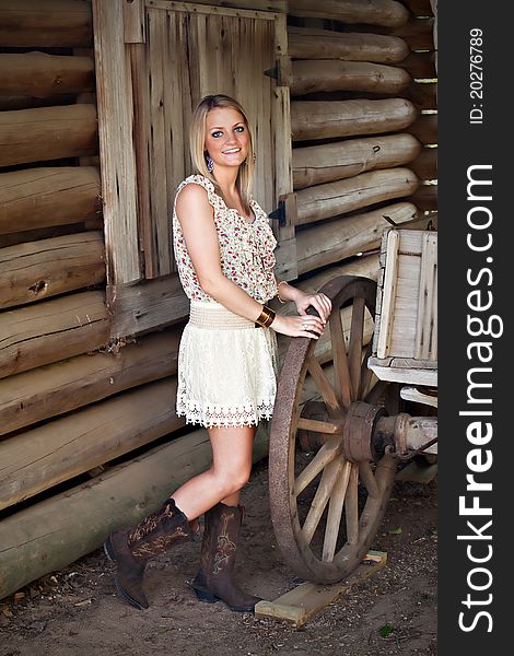 Portrait of beautiful smiling teenage girl standing next to a wagon wheel. Portrait of beautiful smiling teenage girl standing next to a wagon wheel.