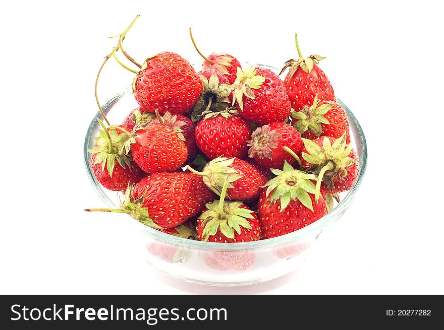 Glass cup with a strawberry scattered on a white background. Glass cup with a strawberry scattered on a white background