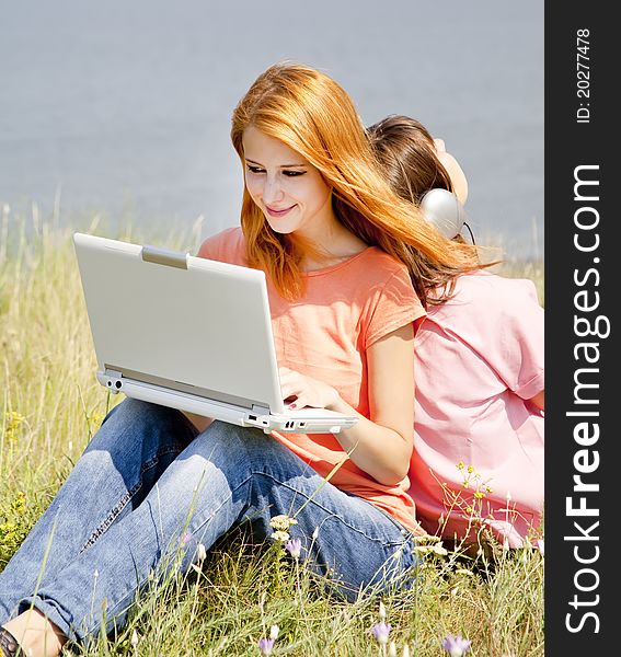 Two girlfriends at countryside with laptop computer.