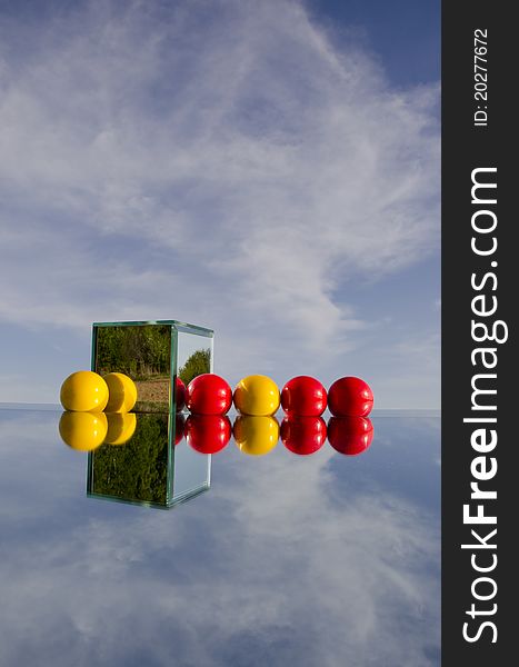 Red And Yellow Balls On Mirror And Sky