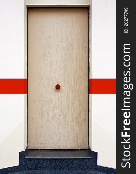 A wood door with a red knob. A wood door with a red knob