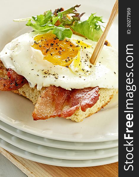 Fried egg and bacon on toasted bread with mixed greens