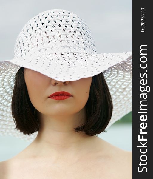 The girl on a beach in a white hat.