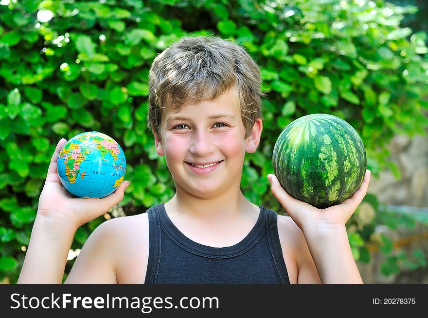 A boy holding a globe and a watermelon shows the difference in size. A boy holding a globe and a watermelon shows the difference in size