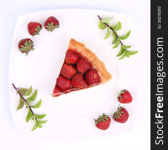 Piece of Strawberry Tart on white plate decorated with strawberries and mint twigs