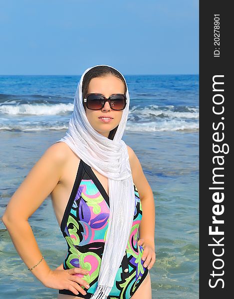 Beautiful girl in dark glasses standing in the sea throwing a white scarf on his head. Beautiful girl in dark glasses standing in the sea throwing a white scarf on his head
