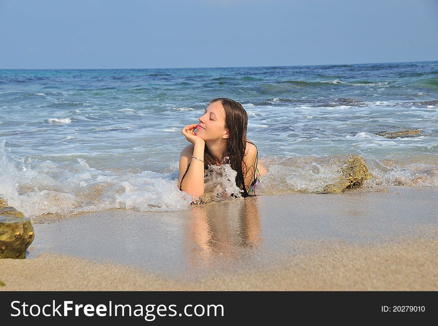 The girl lies on the shore of the sea waves his head in his hand. The girl lies on the shore of the sea waves his head in his hand