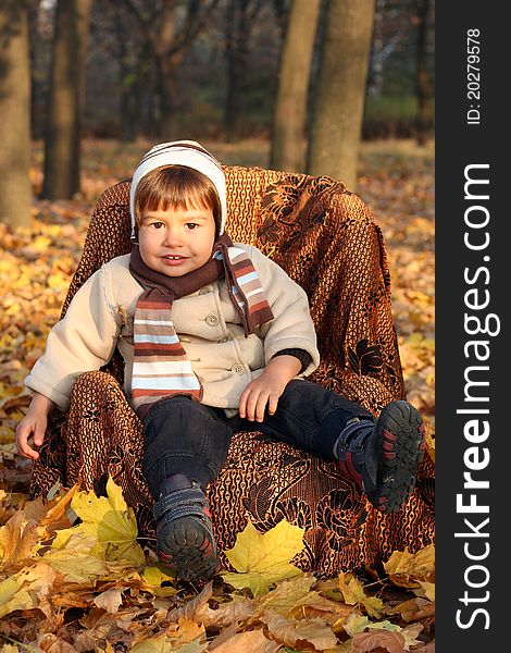 Little Boy Sitting In Chair Outdoors