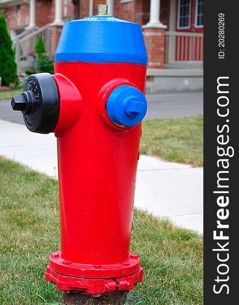 Residential area fire hydrant with red bonnet and blue nozzle caps.