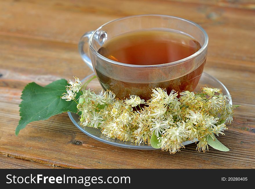 Linden tea on a wooden table. Tea with linden flowers. Cup of tea on the table. Brewed lime beverage. Medicinal tea.