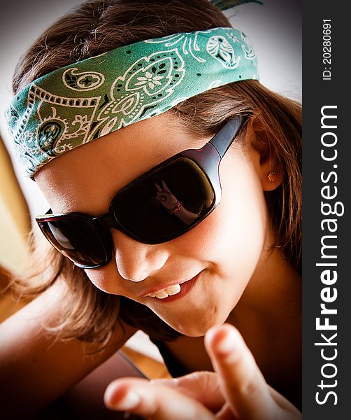 Young girl making the peace sign, reflected in her sunglasses.