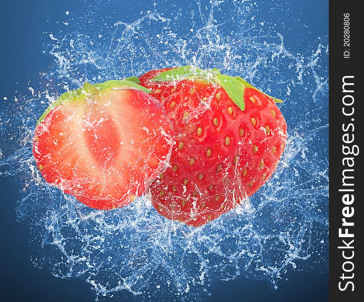 Fresh strawberries in a spray of water on blue