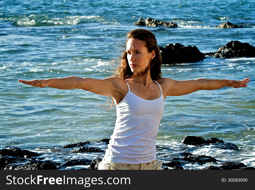 A closeup of a female yogi with her arms outstretched in a warrior pose as she performs yoga on a beach in Maui, Hawaii. A closeup of a female yogi with her arms outstretched in a warrior pose as she performs yoga on a beach in Maui, Hawaii.