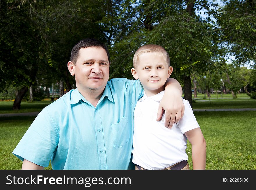 The portrait of the father and the son, stay in park together, are happy. The portrait of the father and the son, stay in park together, are happy