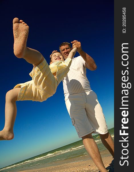 A happy boy tossed into the blue sky by his father at beach. A happy boy tossed into the blue sky by his father at beach