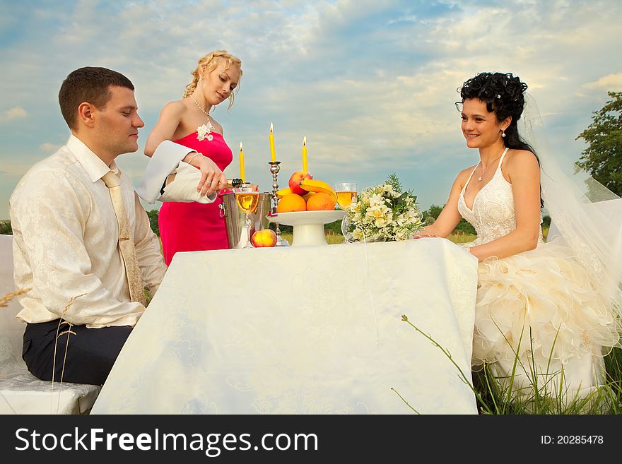 Bride and groom sitting at wedding table on the field