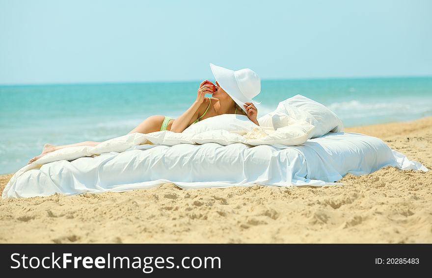 Young beautiful woman eatting a sweet apple in bed on the beach. Young beautiful woman eatting a sweet apple in bed on the beach