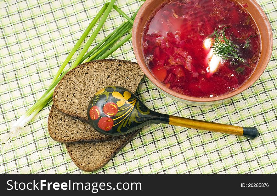 Bowl of a borsch with green onions and a wooden spoon in style Hohloma. Bowl of a borsch with green onions and a wooden spoon in style Hohloma