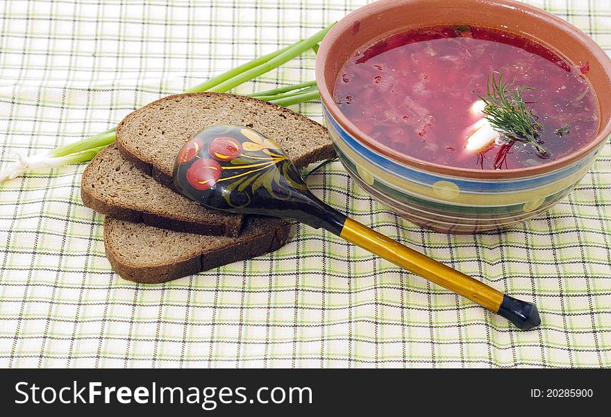 Bowl of a borsch with green onions and a wooden spoon in style Hohloma. Bowl of a borsch with green onions and a wooden spoon in style Hohloma