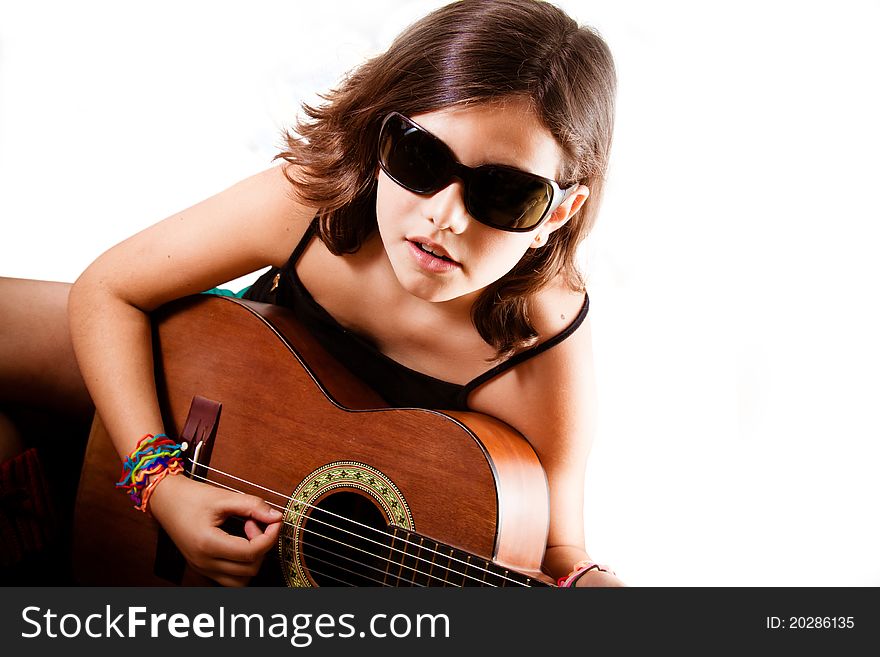 Pre-teen girl playing acoustic guitar wearing sunglasses. White background, copyspace, landscape orientation. Pre-teen girl playing acoustic guitar wearing sunglasses. White background, copyspace, landscape orientation.