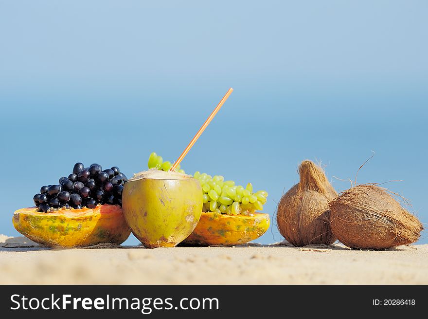 Papaya, coconut, nut and grapes on the sand. Papaya, coconut, nut and grapes on the sand