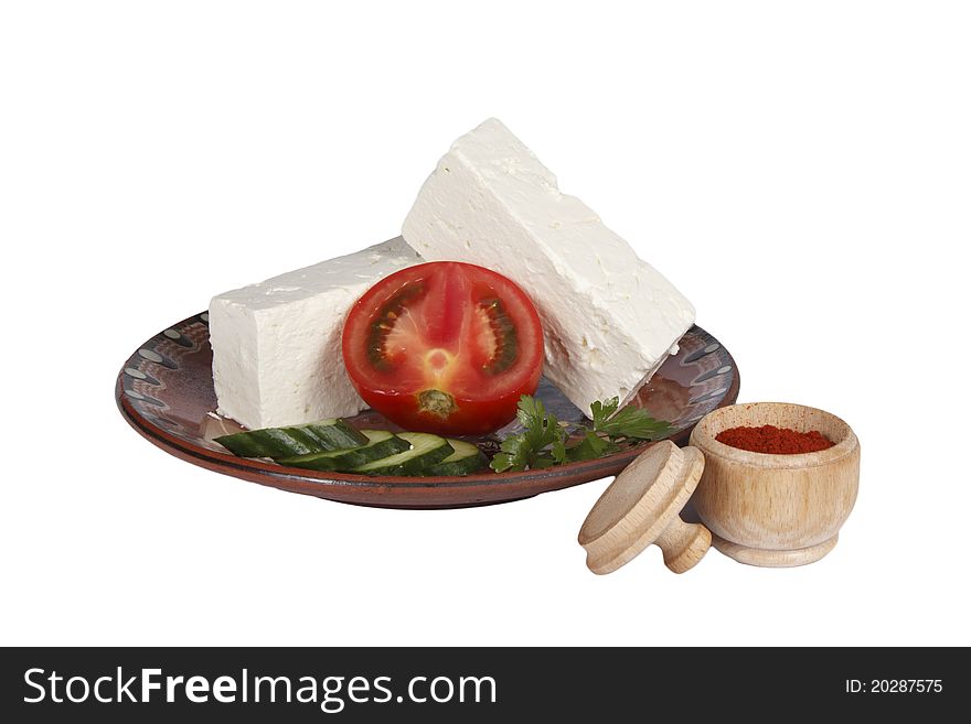 Bulgarian white cheese decorated with tomato and cucumber into a plate isolated on white. Bulgarian white cheese decorated with tomato and cucumber into a plate isolated on white