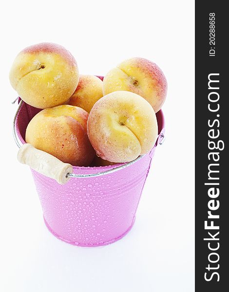 Fresh apricots in a pink bucket on white background
