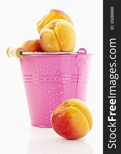 Fresh apricots in a pink bucket on white background