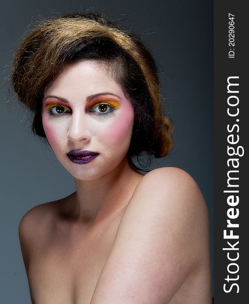 Beautiful young female against Grey with colourful make up