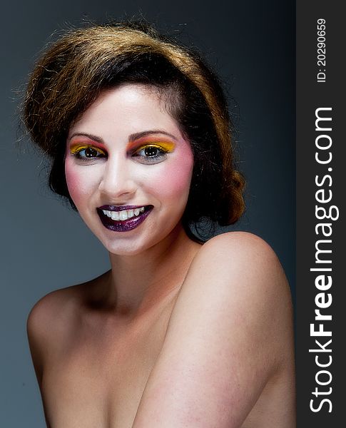 Beautiful young female against Grey with colourful make up