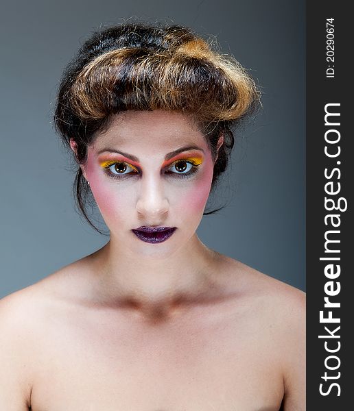 Beautiful young female against Grey with colourful make up