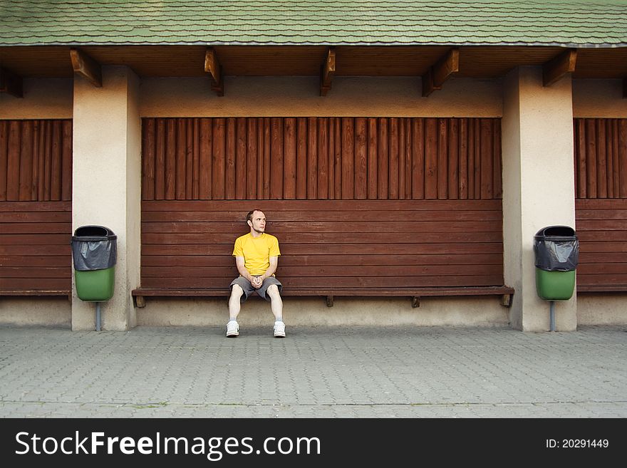 Man in yellow shirt sitting on bench