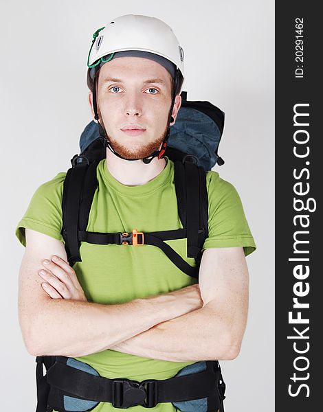 Mountain tourist in helmet and with big backpack standing with crossed hands